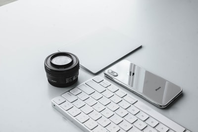 银iPhone X镜头和苹果键盘旁边
